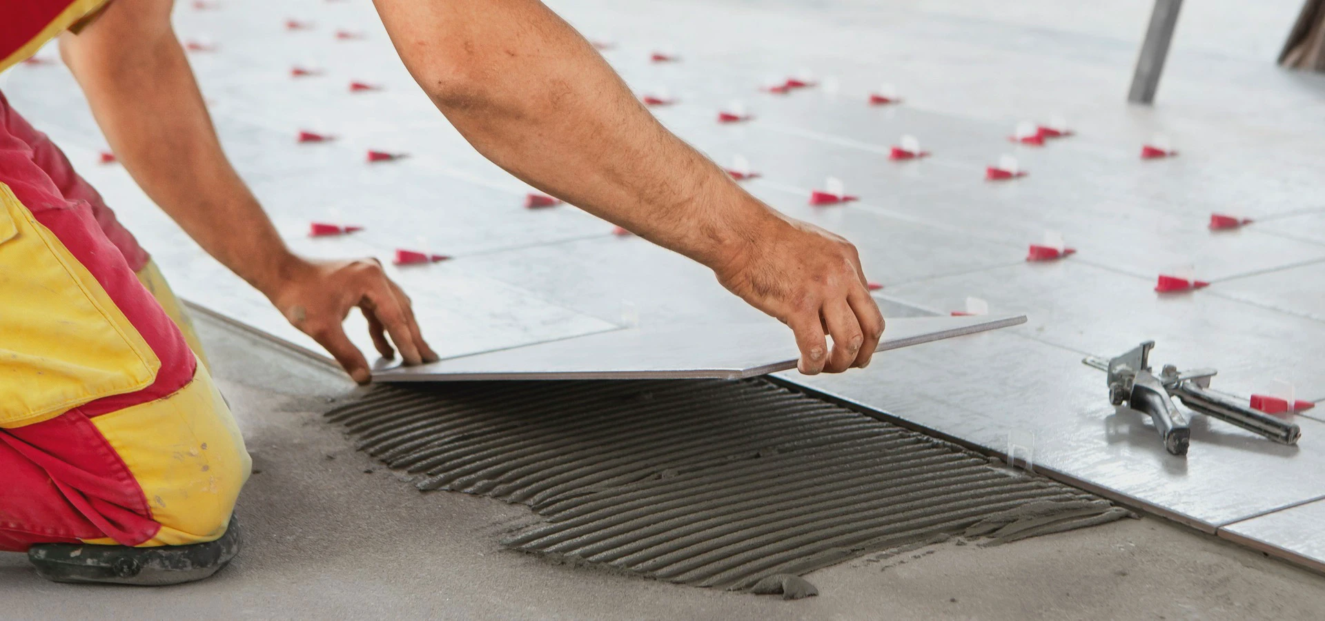 Układanie płytki ceramicznej na warstwie kleju podczas prac glazurniczych